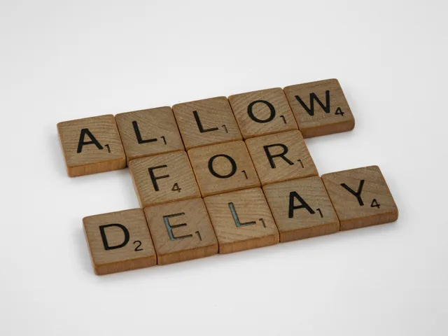 Wooden letter tiles on a white background spelling 'Allow for Delay'. Confrontare pianificazione e gestione delle dipendenze